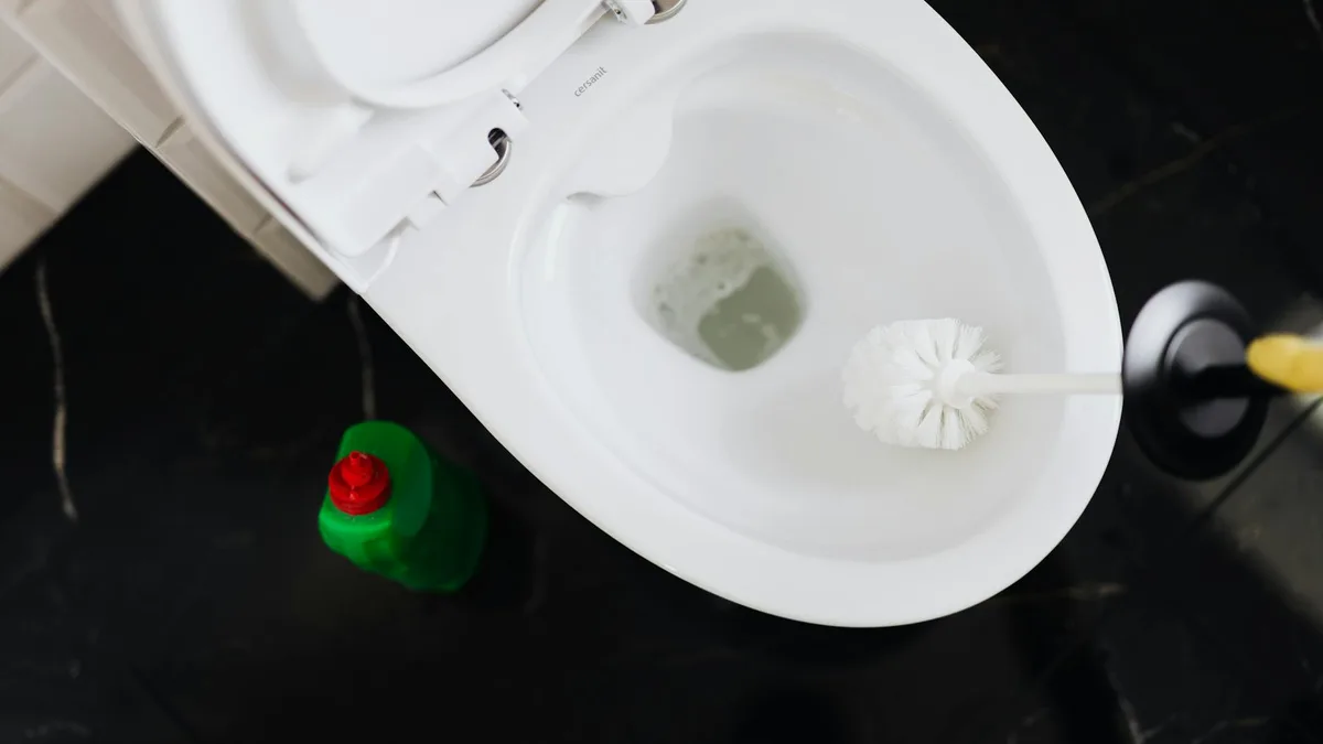 Fachmann behebt verstopfte Toilette mit Rohrspirale in einem modernen Badezimmer